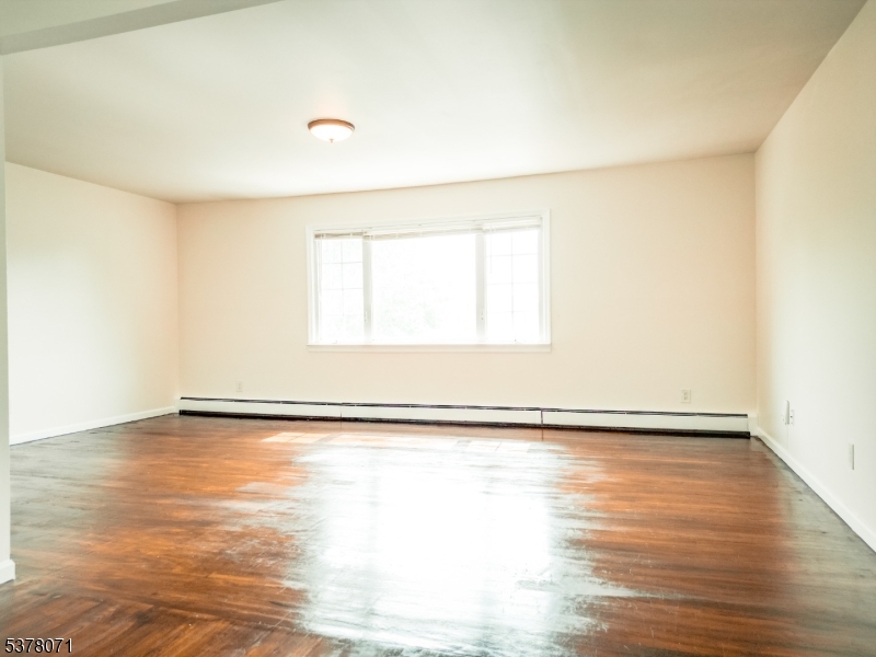 104 Eastern Way, Unit 2 Rutherford, NJ 07070 - Photo 7 of 18 a view of an empty room with wooden floor and a window