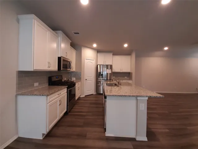 a kitchen with stainless steel appliances granite countertop a stove top oven a sink and a granite counter tops