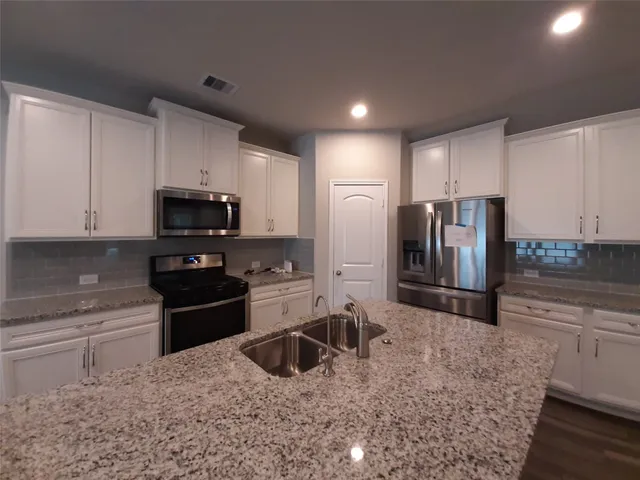 a kitchen with stainless steel appliances granite countertop a refrigerator stove and microwave