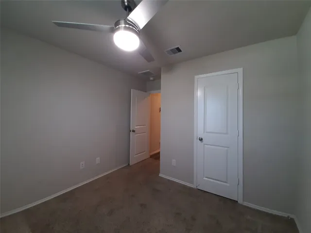 an empty room with closet and a chandelier fan