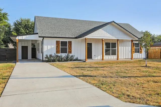 a front view of a house with yard and trees