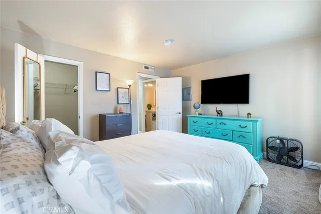 a large white bed in a bedroom and a flat tv screen