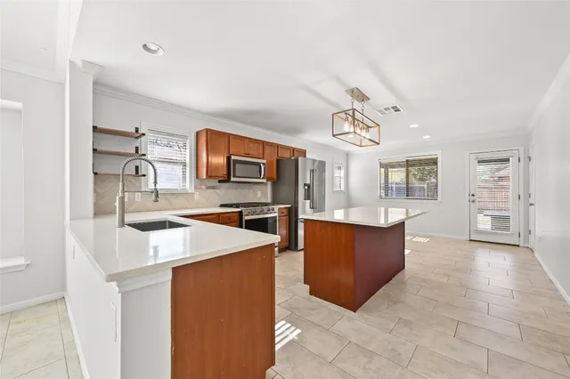 a large kitchen with stainless steel appliances a stove a sink a refrigerator and a dining table with wooden floor