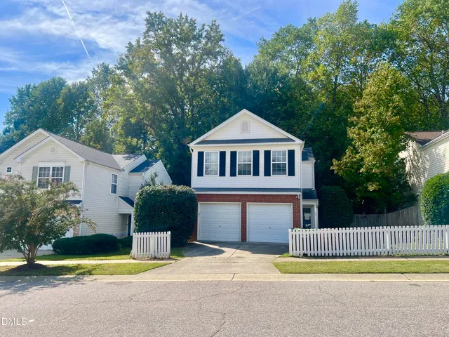 a front view of a house with a garden and trees