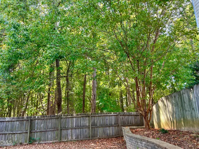 a view of a backyard with wooden fence and a large tree