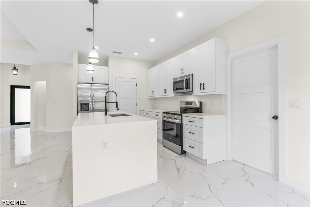412 Fitch Avenue Lehigh Acres, FL 33972 - Photo 12 of 50 a kitchen with kitchen island a sink stainless steel appliances and white cabinets