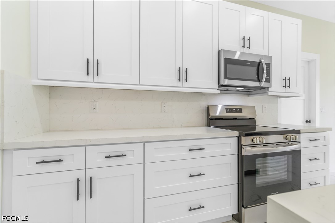 412 Fitch Avenue Lehigh Acres, FL 33972 - Photo 17 of 50 a kitchen with white cabinets and stainless steel appliances