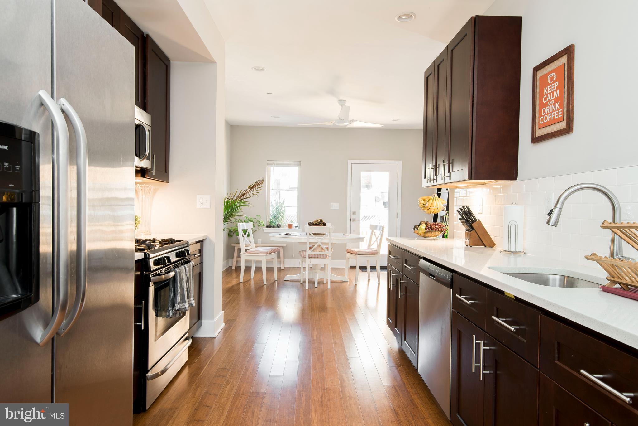 a kitchen with stainless steel appliances a sink dishwasher a refrigerator and wooden floor