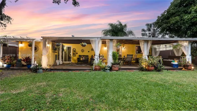 a view of a patio with table and chairs potted plants and large tree