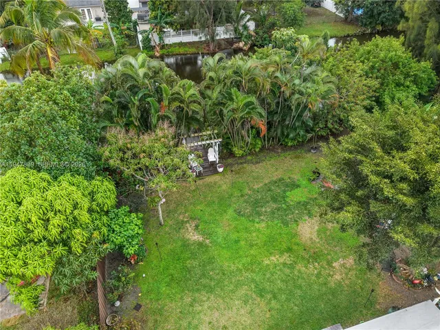 a view of a backyard with table and chairs potted plants and a large tree