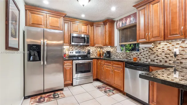 a kitchen with stainless steel appliances granite countertop a refrigerator a stove a sink and dishwasher