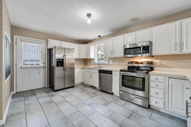 a kitchen with stainless steel appliances granite countertop a refrigerator sink and stove
