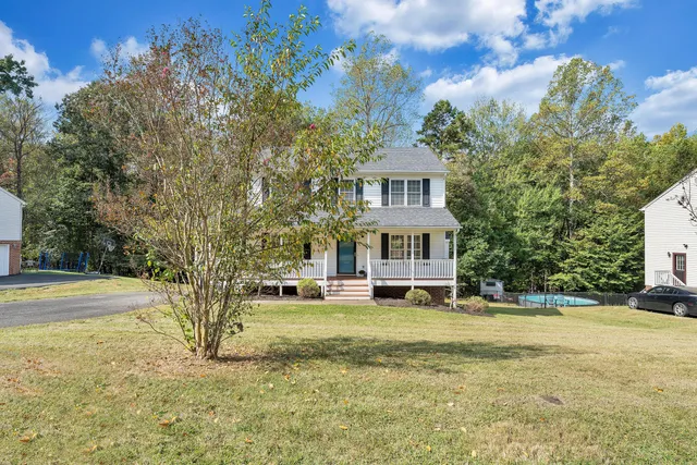 a view of a house with a big yard and large trees