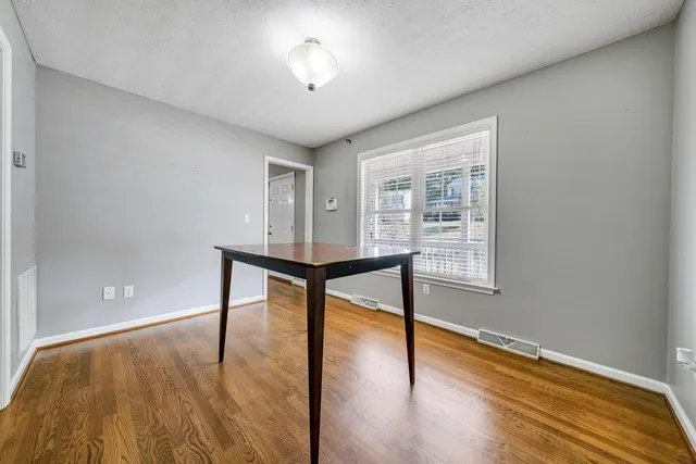 a view of an empty room with a window and wooden floor