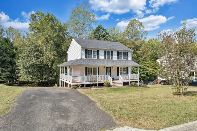 a view of a house with a big yard and large trees