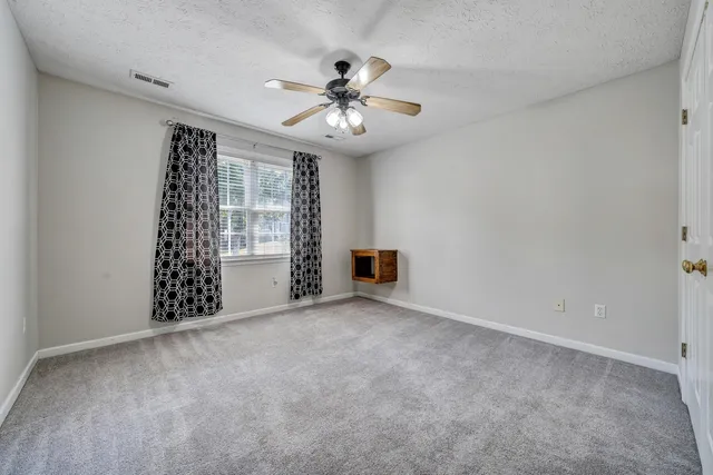 a view of an empty room with chandelier fan and a window