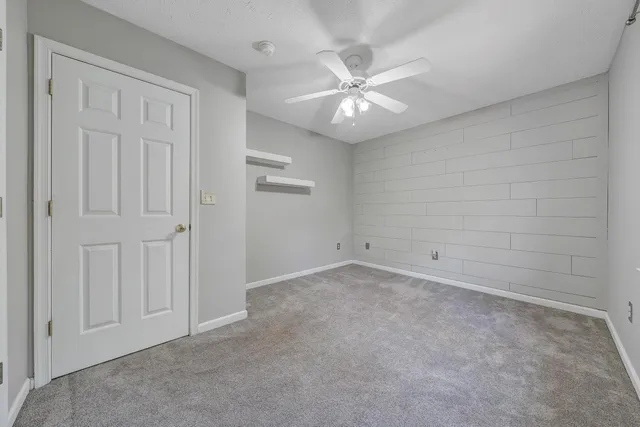 an empty room with a chandelier fan and closet area