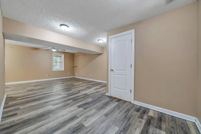 a view of an empty room with wooden floor and window