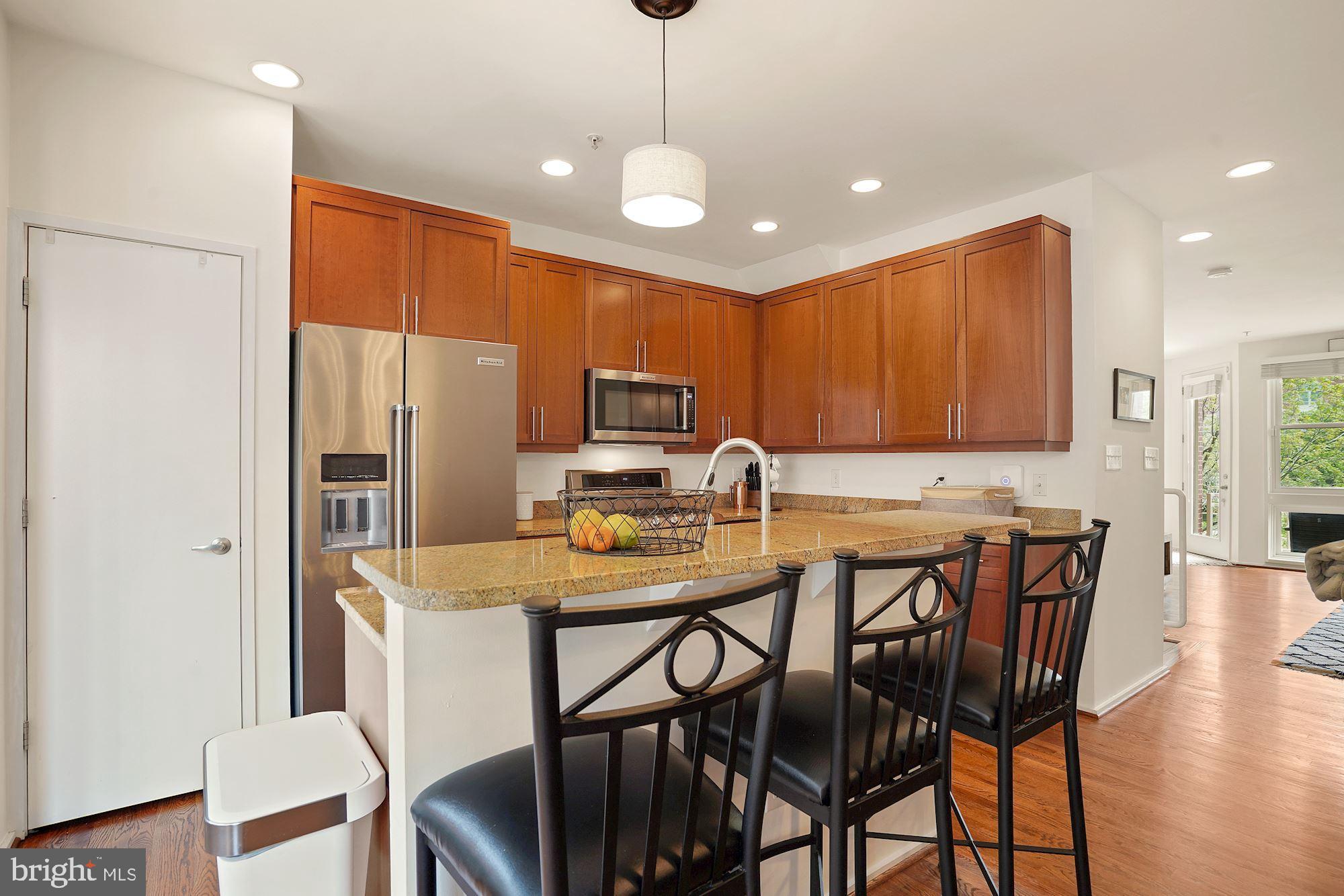 1618 North Rhodes Street Arlington, VA 22209 - Photo 12 of 33 a kitchen with stainless steel appliances granite countertop a dining table chairs refrigerator and microwave