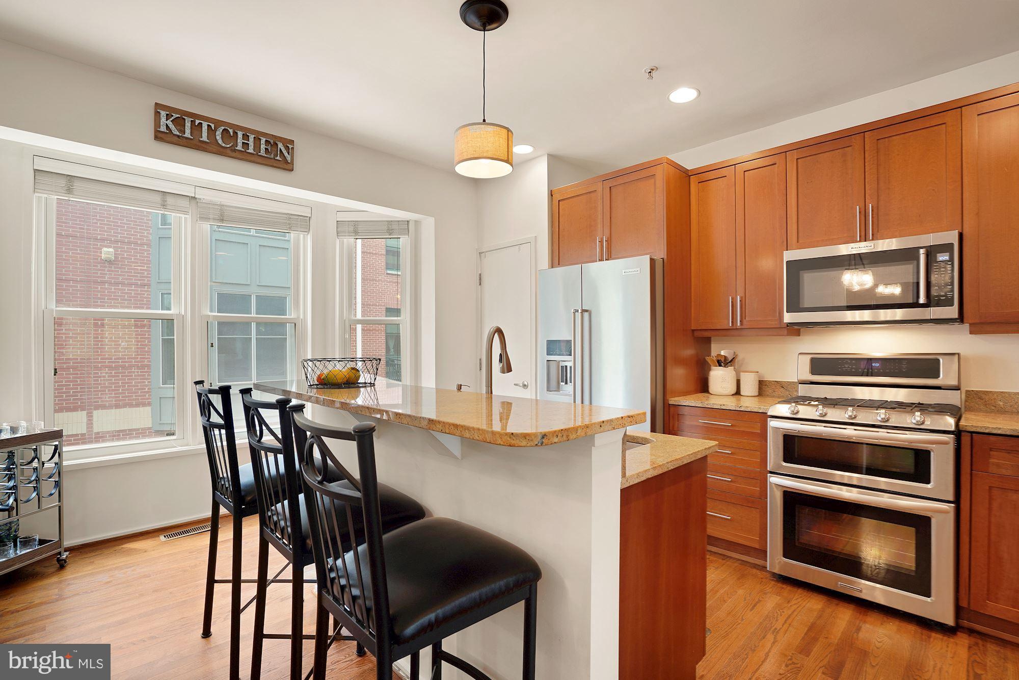 1618 North Rhodes Street Arlington, VA 22209 - Photo 10 of 33 a kitchen with stainless steel appliances granite countertop a stove a refrigerator a kitchen island a dining table and chairs with wooden floor