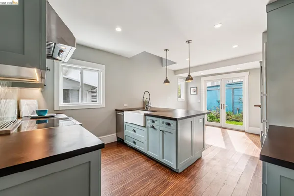 a kitchen with stainless steel appliances a stove a sink dishwasher and a dining table with wooden floor