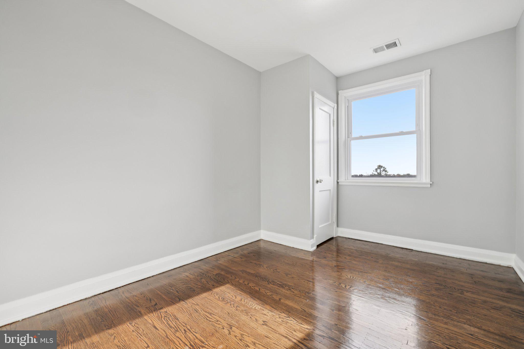 3427 Woodstock Avenue Baltimore, MD 21213 - Photo 19 of 46 an empty room with wooden floor and windows