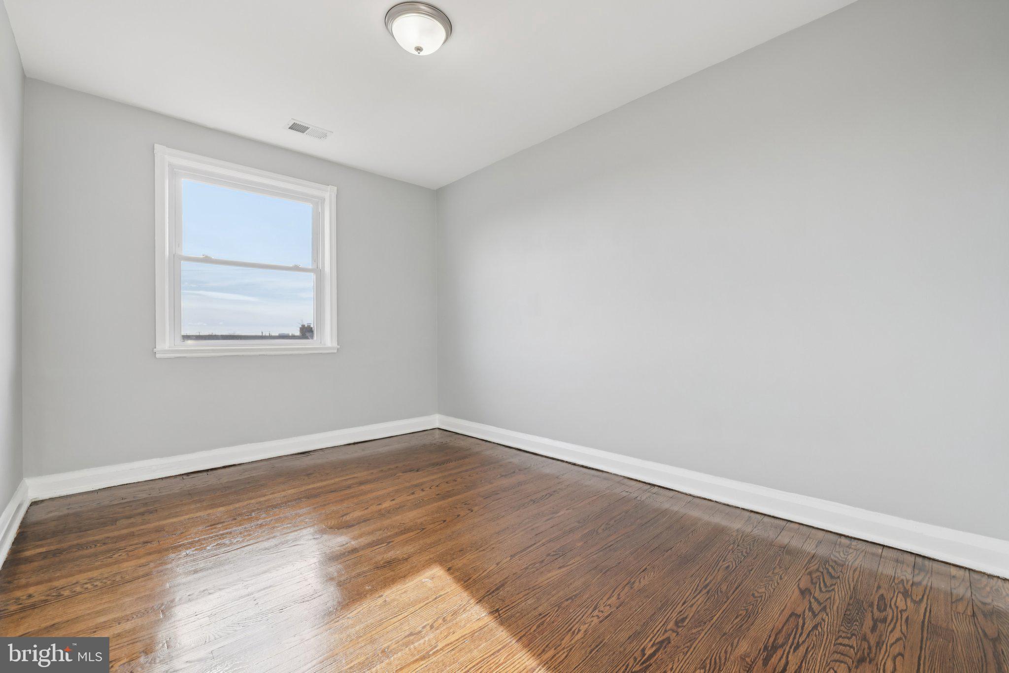 3427 Woodstock Avenue Baltimore, MD 21213 - Photo 21 of 46 an empty room with wooden floor and windows