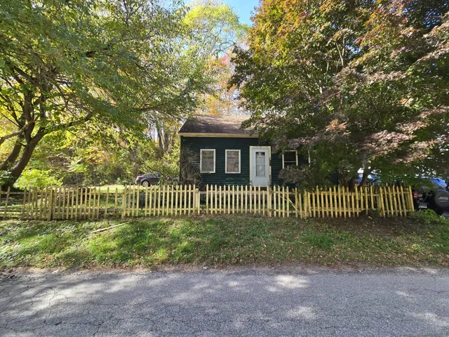 a view of a house with a small yard and a large tree
