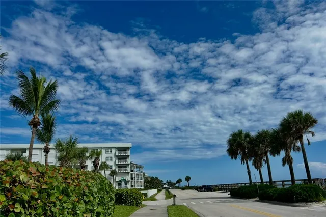 a front view of multi story residential apartment building with a yard and palm trees