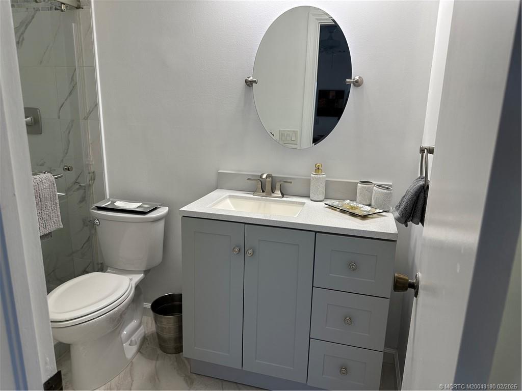 755 Saturn Street, Unit F205 Jupiter, FL 33477 - Photo 13 of 19 a bathroom with a toilet sink and mirror