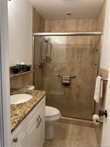 a bathroom with a granite countertop sink toilet and shower