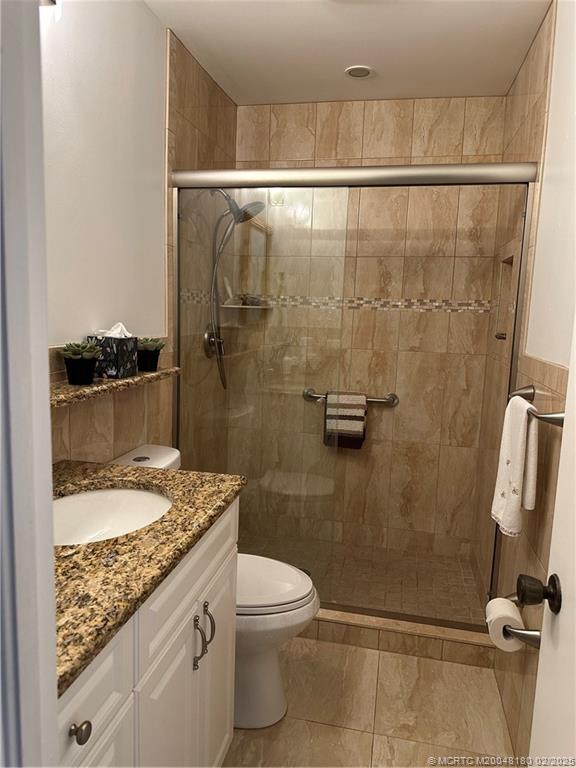 755 Saturn Street, Unit F205 Jupiter, FL 33477 - Photo 17 of 19 a bathroom with a granite countertop sink toilet and shower