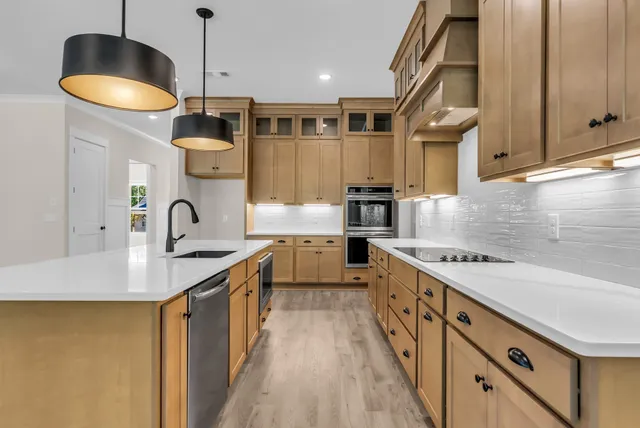 a kitchen with stainless steel appliances granite countertop a sink a stove and a wooden floors