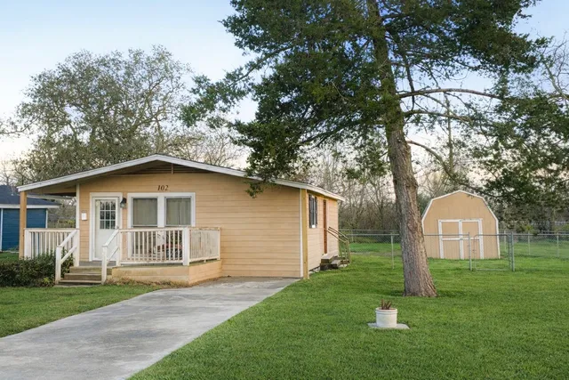 a view of a house with a yard and large tree