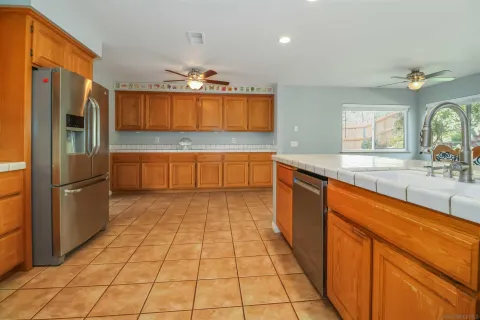 a large kitchen with a large counter top a sink a refrigerator and a counter top space