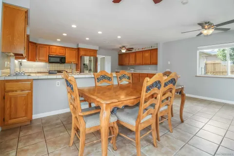 a dining table with a kitchen island white cabinetry a sink and a window
