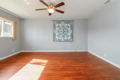 a view of an empty room with a window and wooden floor
