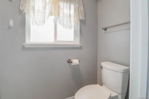 a white toilet sitting next to a window in a bathroom
