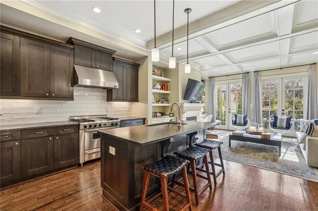 a large kitchen with stainless steel appliances granite countertop a stove and a wooden floors