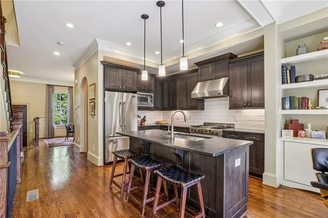 a kitchen with stainless steel appliances granite countertop a stove refrigerator and a wooden floor