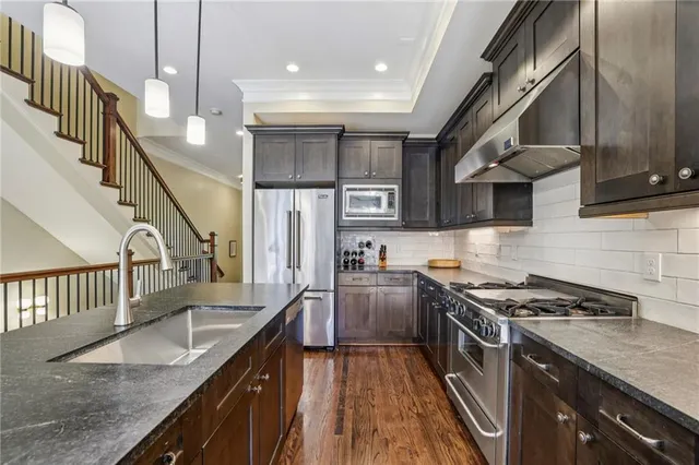 a kitchen with stainless steel appliances granite countertop a sink a stove and a wooden floors