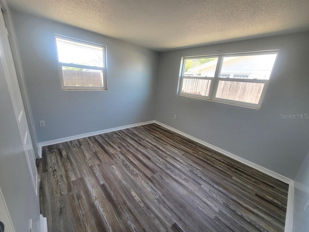 10225 Gardenia Lane Port Richey, FL 34668 - Photo 11 of 17 a view of an empty room with wooden floor and a window