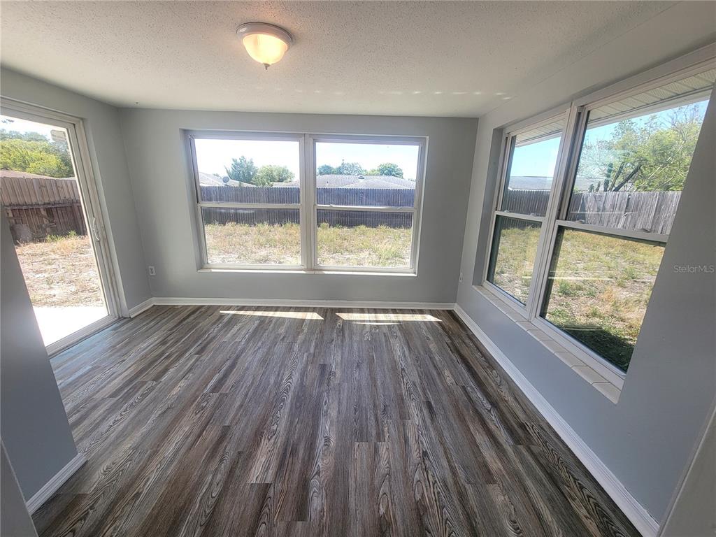 10225 Gardenia Lane Port Richey, FL 34668 - Photo 13 of 17 a view of an empty room with wooden floor and a window