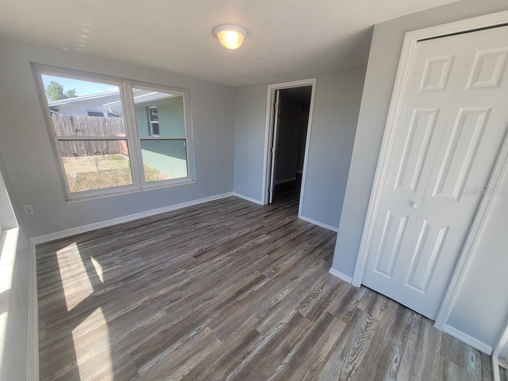10225 Gardenia Lane Port Richey, FL 34668 - Photo 14 of 17 a view of an empty room with wooden floor and a window