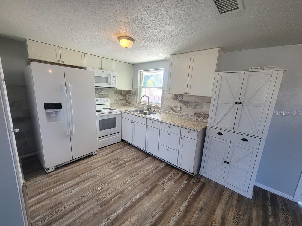 10225 Gardenia Lane Port Richey, FL 34668 - Photo 6 of 17 a kitchen with white cabinets and white appliances