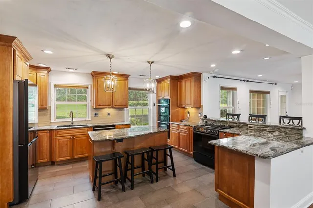 a kitchen with stainless steel appliances granite countertop a stove a sink a refrigerator and a dining table