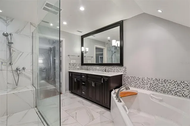 a bathroom with a granite countertop sink a mirror a bathtub and shower