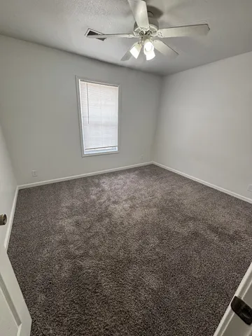 en empty room with windows and ceiling fan