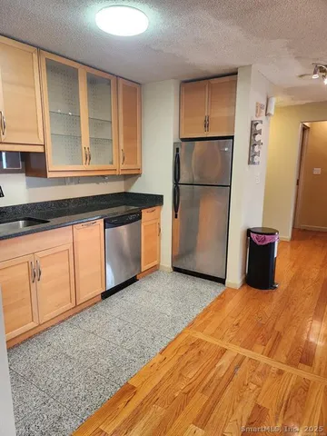 a kitchen with granite countertop white cabinets and refrigerator
