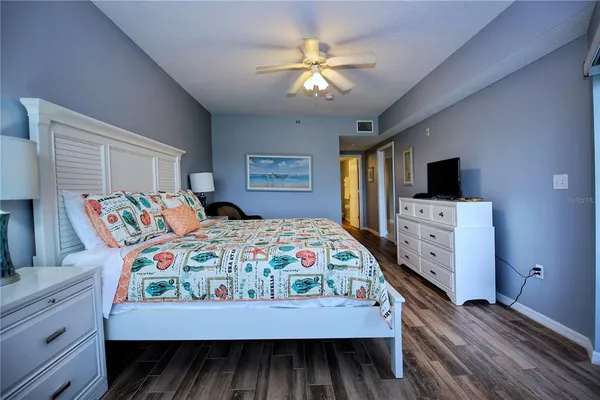 a bedroom with a bed and a flat tv screen on dresser